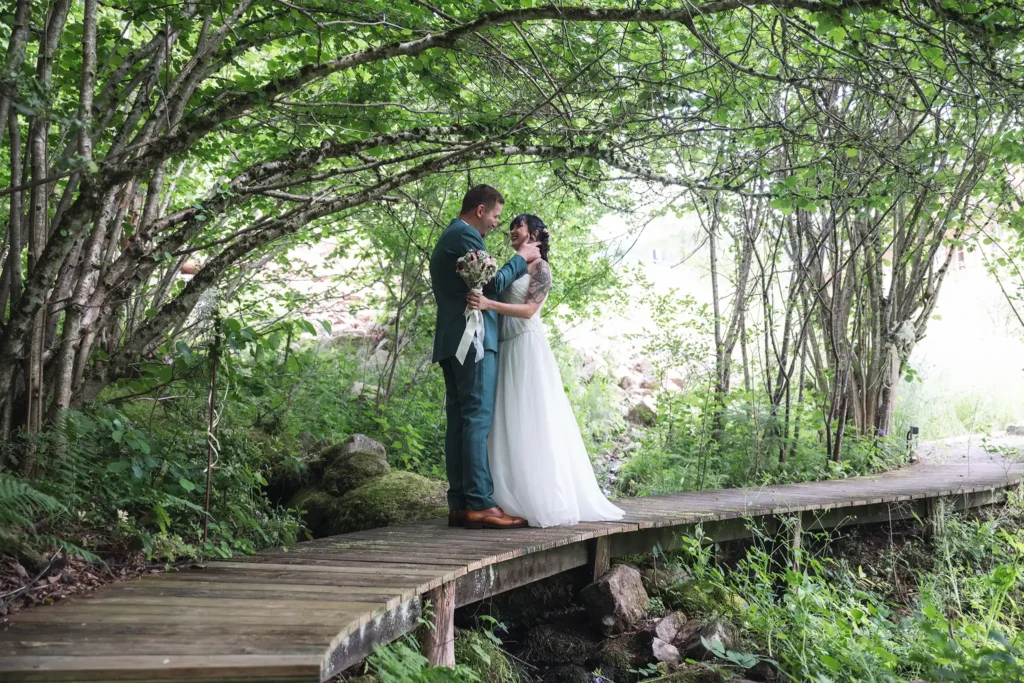 Couple de mariés sur une passerelle en bois dans la forêt de la Ferme Émeraude à Gérardmer