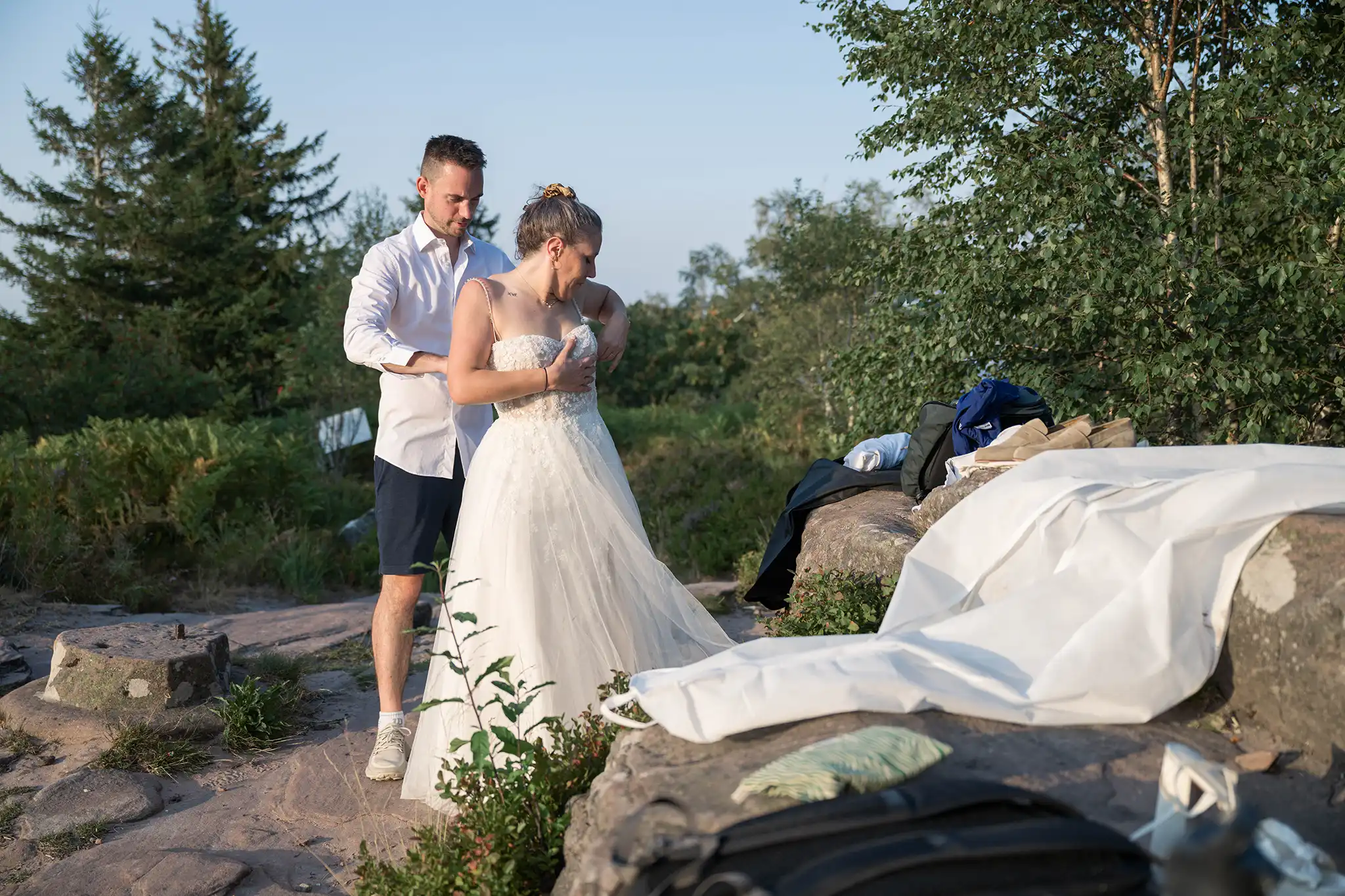 Le marié ferme la robe de la mariée au sommet du Donon avant une séance photo day after dans les Vosges.
