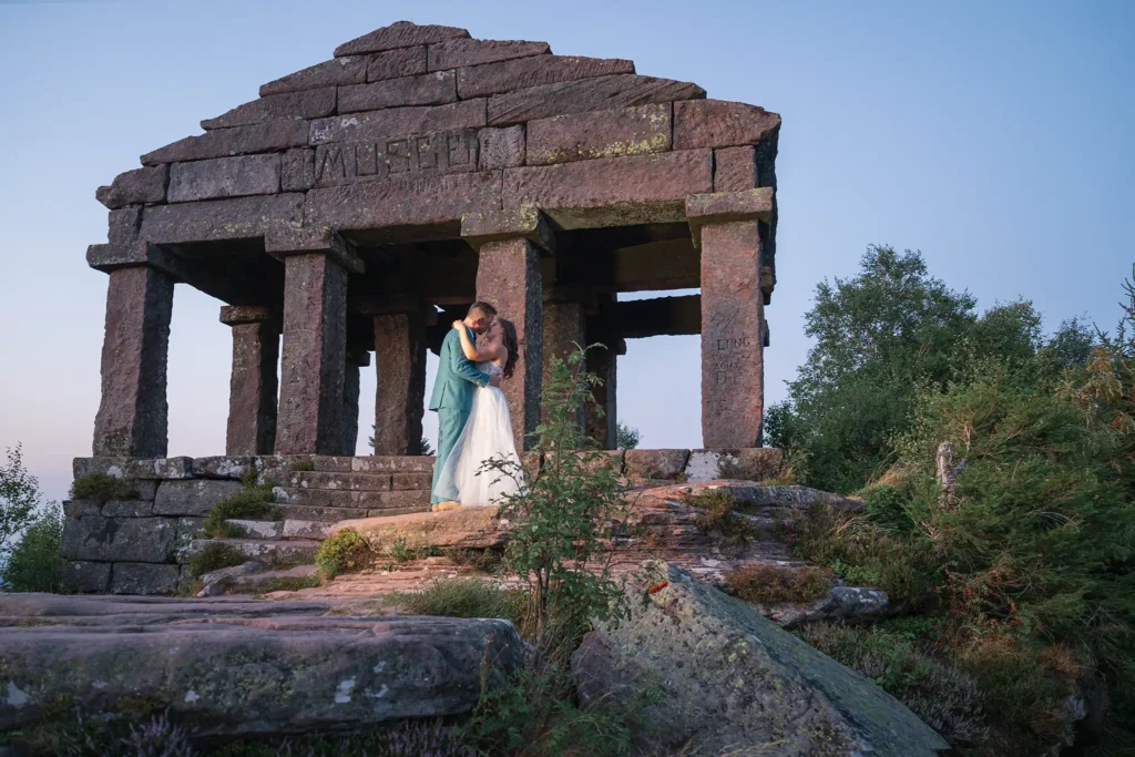 Couple de mariés s'embrassant devant le temple du Donon lors d'une séance photo day after au coucher du soleil dans les Vosges.