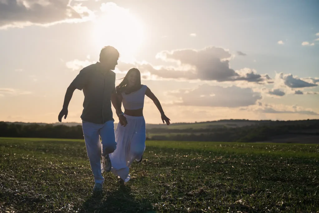 Couple courant dans un champ pendant une séance de fiançailles près de Dieulouard